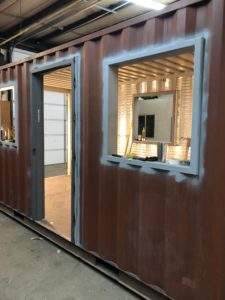 Steel shipping container with cut outs for a door and window and wired with electricity.