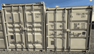 Two tan storage containers with the short, door end facing the camera.  One container is a high cube and slightly taller than the standard container.