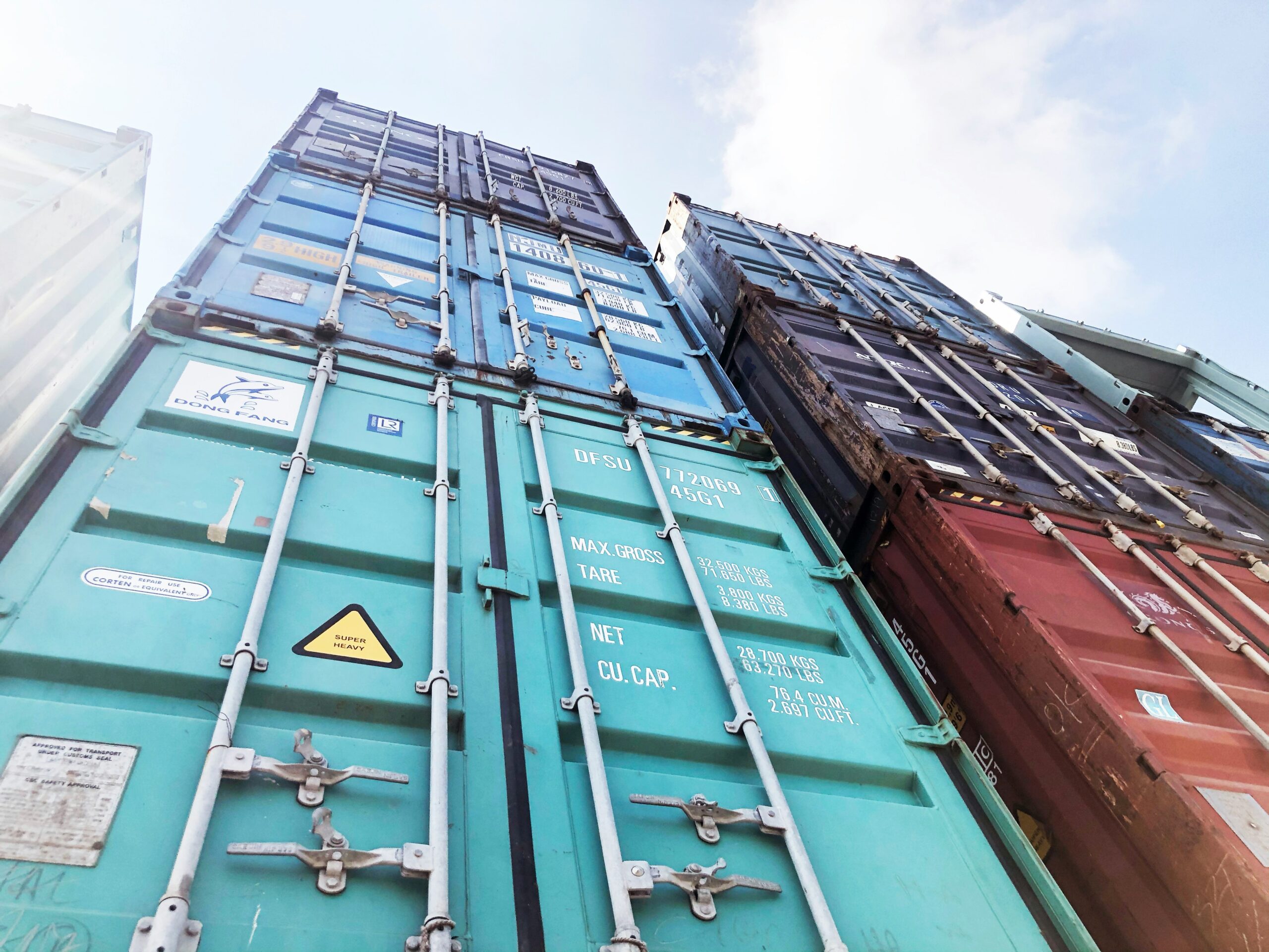 Brightly painted shipping containers stacked three high on top of each other with the door facing the camera.